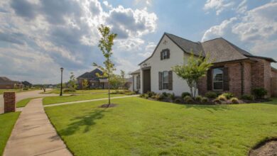 white and brown house near green grass field under white clouds and blue sky during daytime