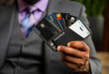 a man in a suit holding four credit cards