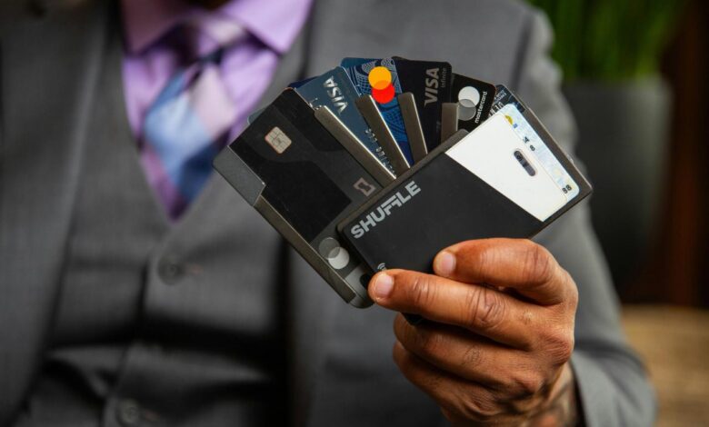 a man in a suit holding four credit cards