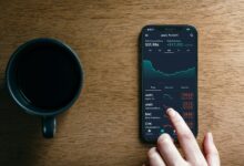 a hand holding a phone next to a cup of coffee