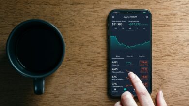 a hand holding a phone next to a cup of coffee