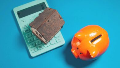 Calculator, piggy bank, and house model on blue background