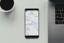 a cell phone sitting on top of a desk next to a laptop