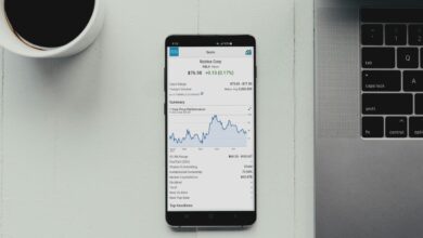 a cell phone sitting on top of a desk next to a laptop