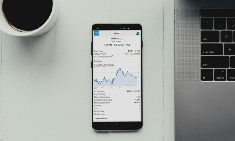 a cell phone sitting on top of a desk next to a laptop